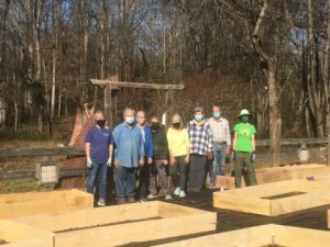 Group of volunteers standing in community garden with completed raised beds.