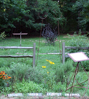 Abstract metal sculpture, in the background of a garden.